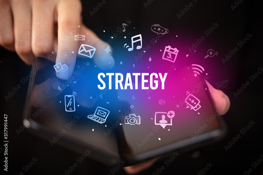 Businessman holding a foldable smartphone with STRATEGY inscription, social media concept Businessman holding a foldable smartphone with STRATEGY inscription, social media concept