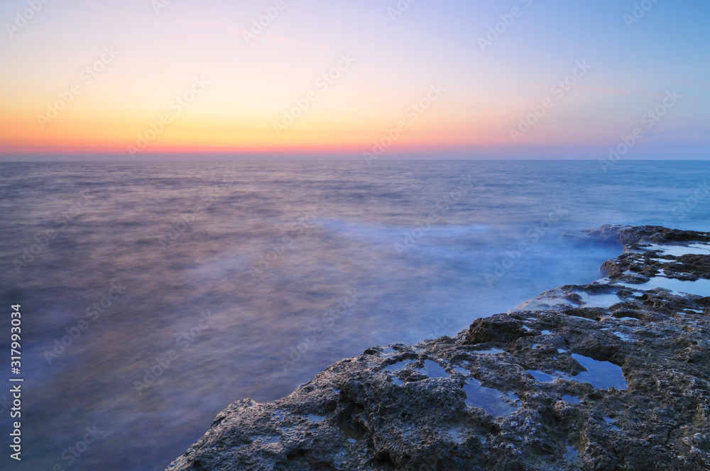 Beautiful pink sunset and water stones with green moss over Black sea