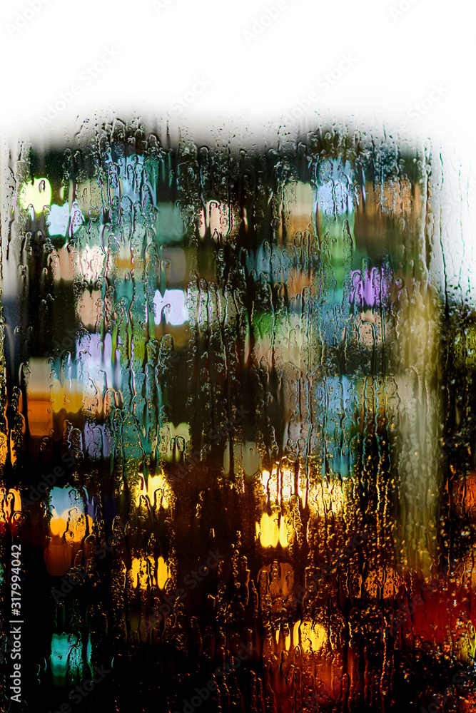 Naklejka premium Glass window with raindrops on the background of blurred lights of the city.