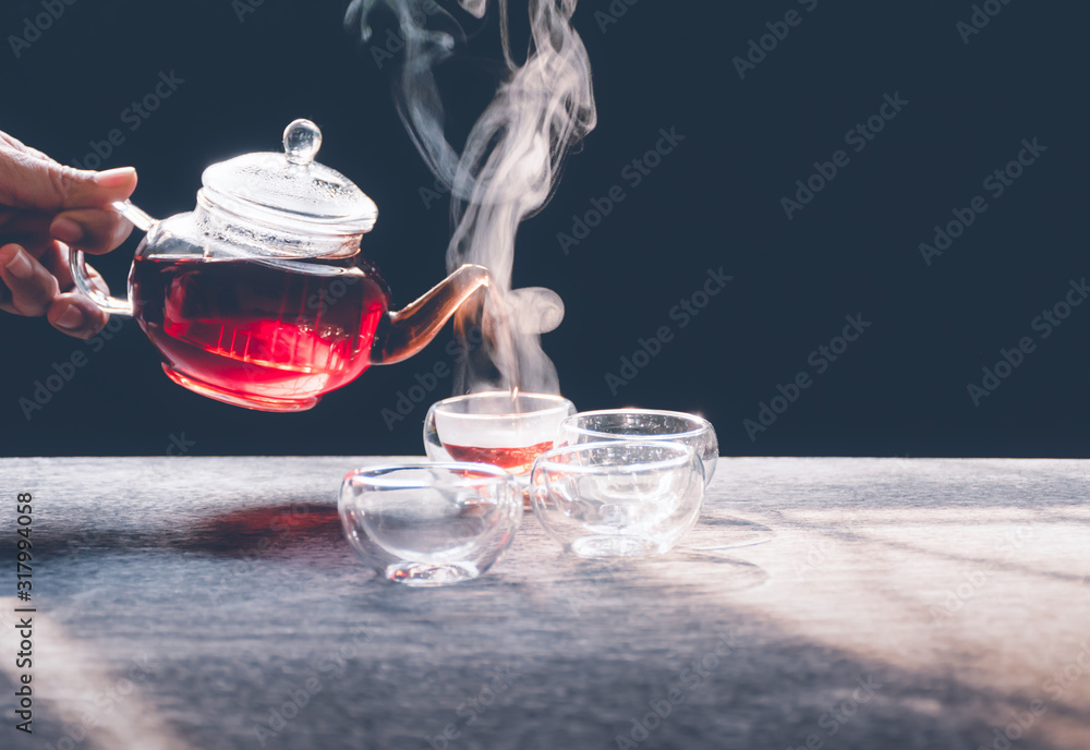 The steam from a cup or pot of tea on the old wood table and black background with nature light by window in the morning, Warm drinks make good healthy, Selective focus. The steam from a cup or pot of tea on the old wood table and black background with nature light by window in the morning, Warm drinks make good healthy, Selective focus.