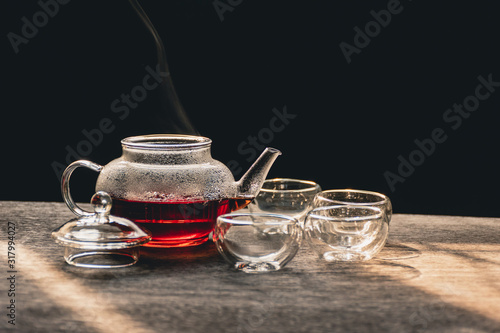 The steam from a cup or pot of tea on the old wood table and black background with nature light by window in the morning, Warm drinks make good healthy, Selective focus.