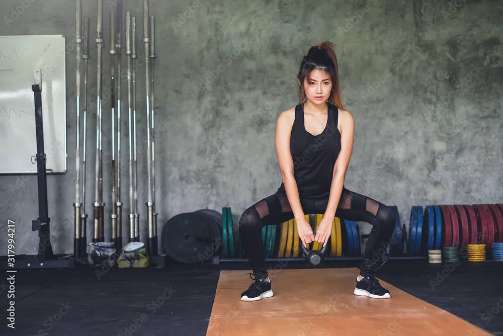Young asian woman lifting a dumbbell during an exercise class at gym ...