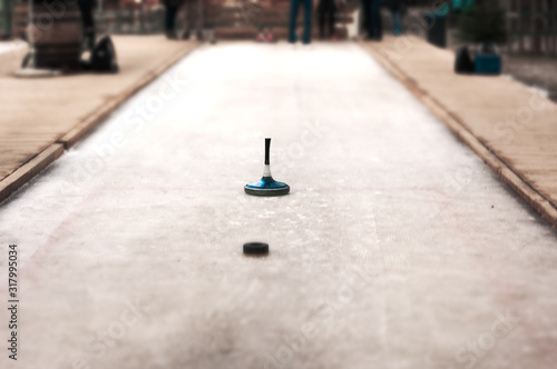 Eistockschießrunde in rustikaler Ambiente: Ein blauer Eisstock nähert sich der Daube