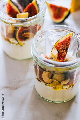Dessert of sour cream, vanilla, figs, nuts, honey and blue cheese in a glass on a marble background