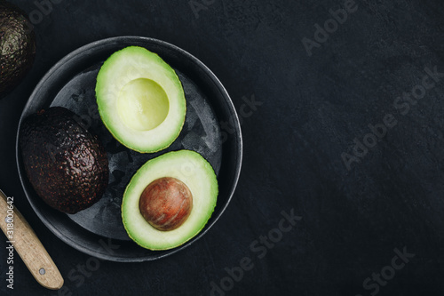 Raw avocado on dark stone background. Fresh green ripe avocado for guacamole.