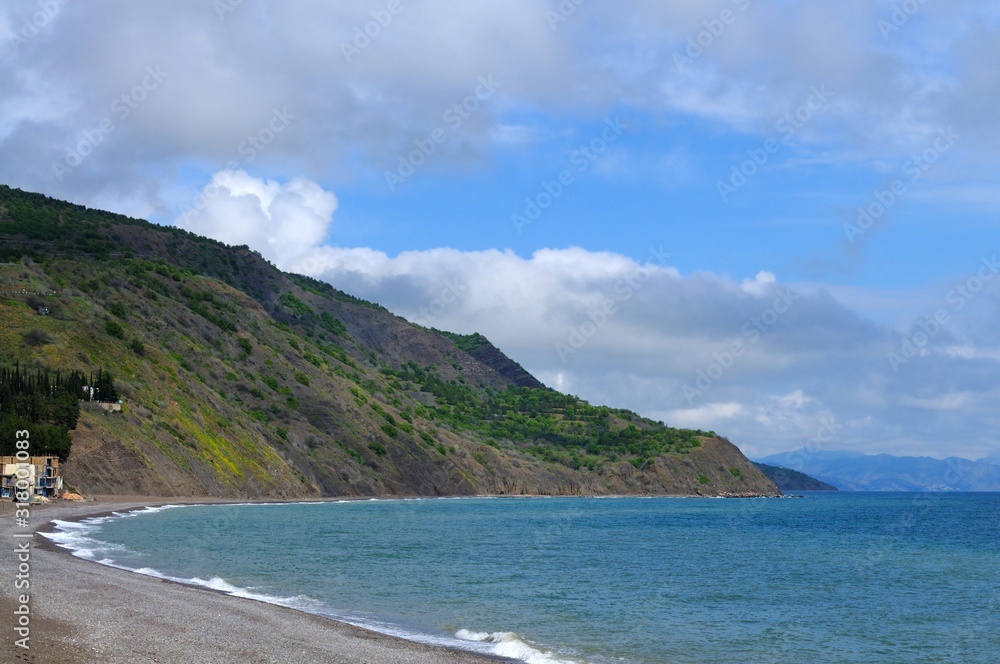 Sea shore and rocky beach, blue cloudy sky