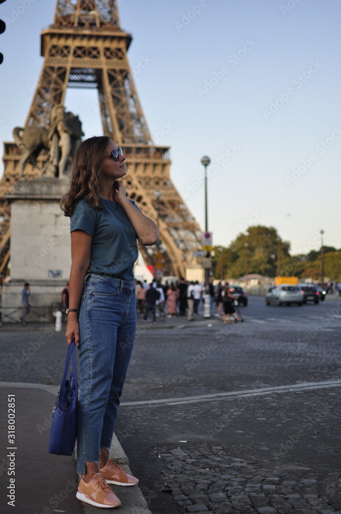 young Caucasian long-haired woman in Paris against the Eiffel Tower in summer. Tourist walk in Europe.