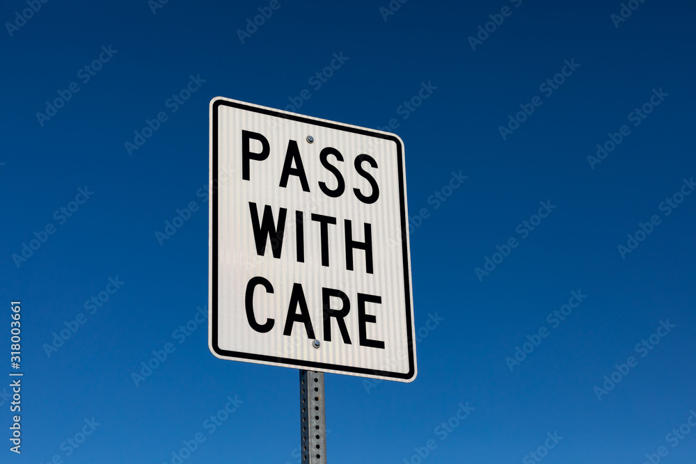 closeup angled view of pass with care reflective street sign. Isolated on deep blue sky background closeup angled view of pass with care reflective street sign. Isolated on deep blue sky background