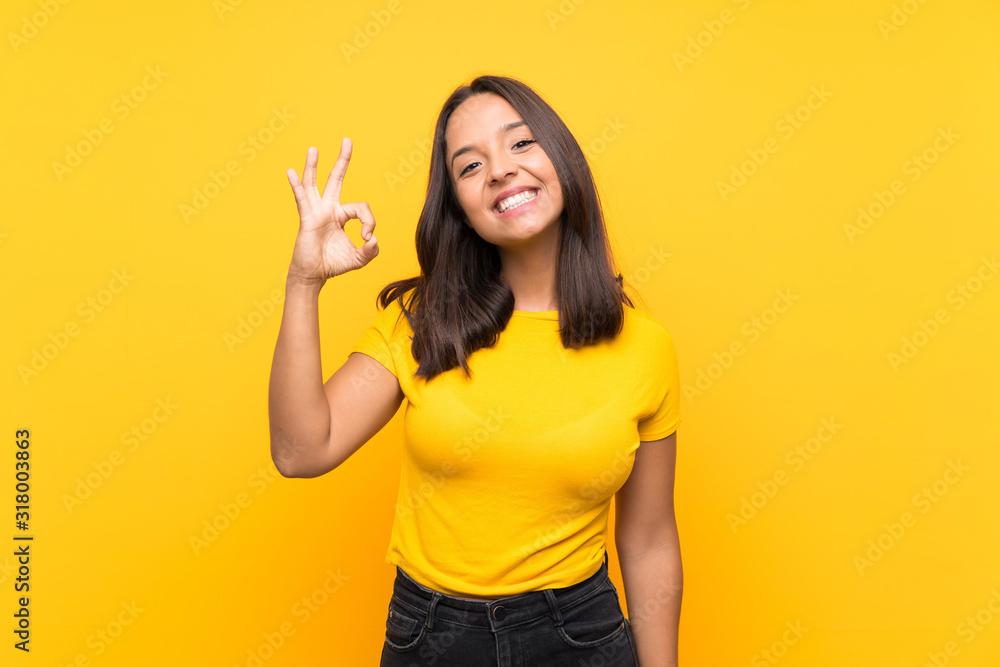 Young brunette girl over isolated background showing ok sign with fingers Young brunette girl over isolated background showing ok sign with fingers