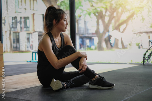 Relaxing after training. Young asian woman sitting and relaxing after her workout at gym.
