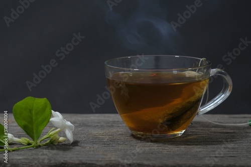 Hot jasmine tea with smoke in a glass in black background