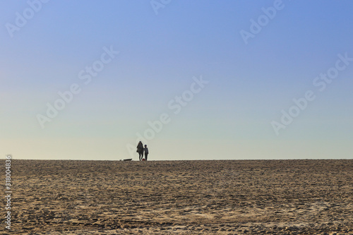 Group of people walking on the beach at sunset