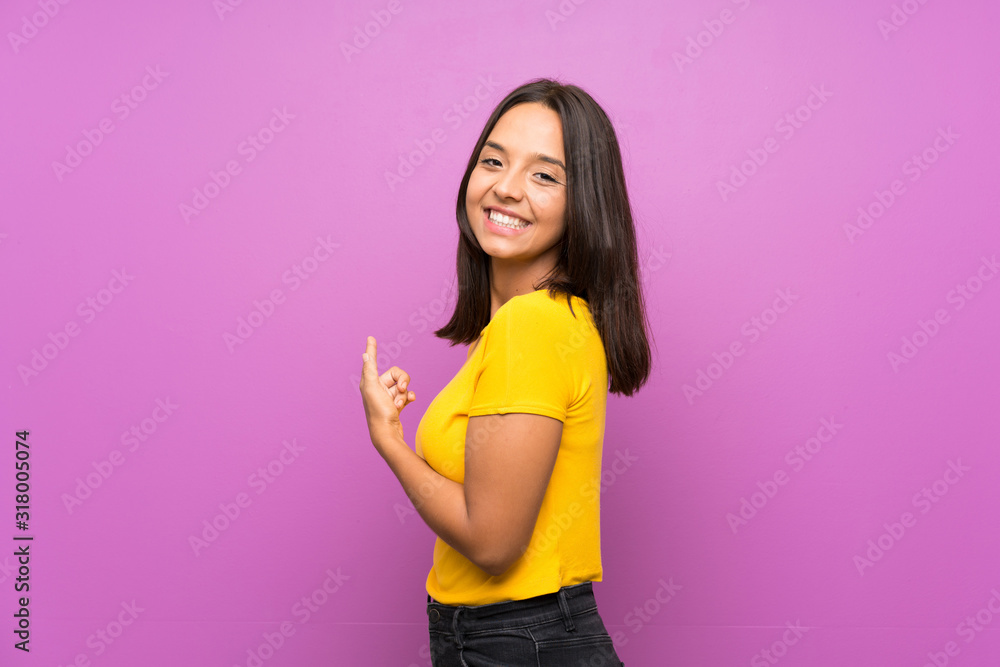 Young brunette girl over isolated background pointing back Young brunette girl over isolated background pointing back