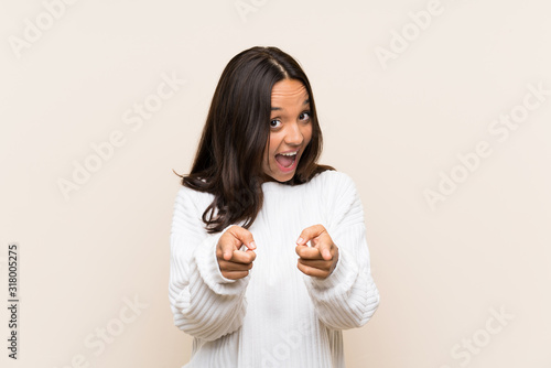 Young brunette woman with white sweater over isolated background points finger at you