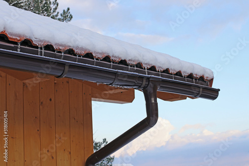 Dachrinne mit Schnee und Eiszapfen an einem Holzhaus mit Regenrinne im Winter photo