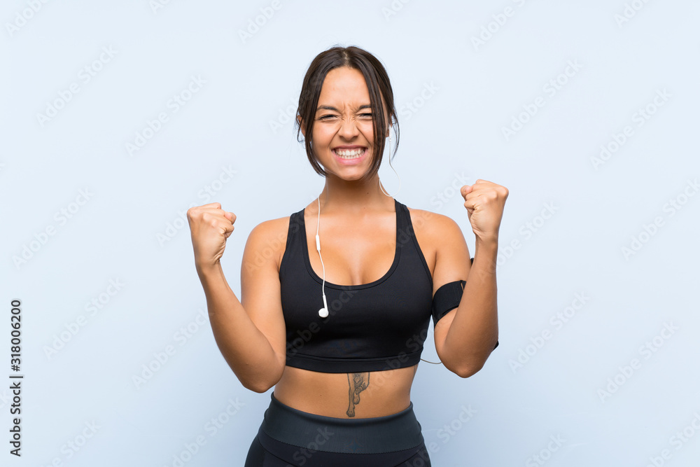 Young sport girl over isolated blue background celebrating a victory Young sport girl over isolated blue background celebrating a victory