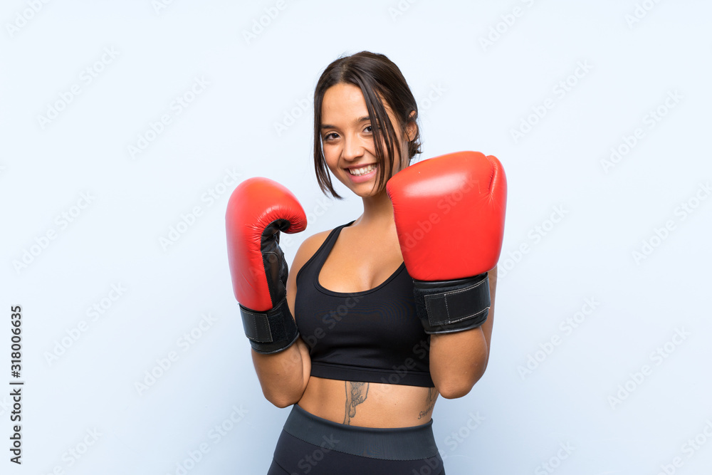 Young sport girl with boxing gloves over isolated blue background