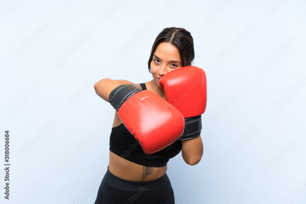 Young sport girl with boxing gloves over isolated blue background Young sport girl with boxing gloves over isolated blue background