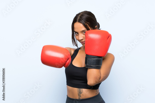 Young sport girl with boxing gloves over isolated blue background