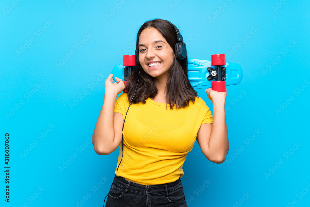 Young skater woman over isolated blue background Young skater woman over isolated blue background