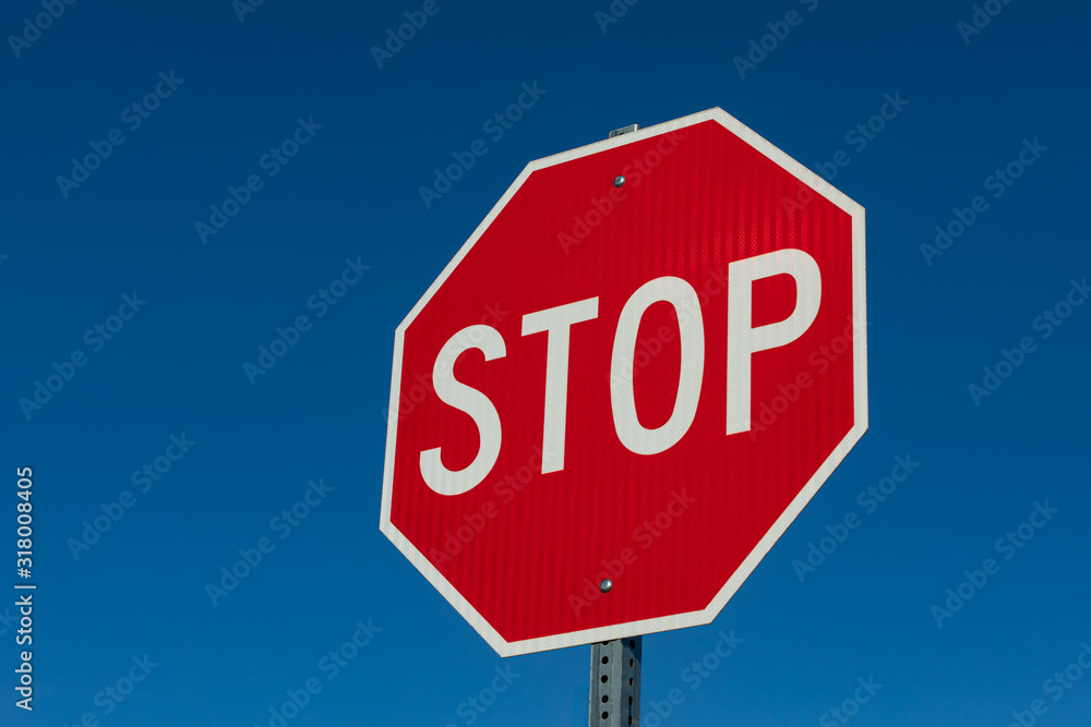 Closeup angled view of reflective stop sign isolated on deep blue sky background Closeup angled view of reflective stop sign isolated on deep blue sky background