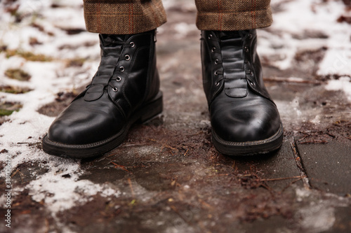 Female feet in black boots, winter walking in snow
