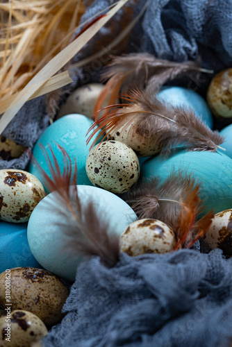 Blue and turquoise painted chicken and quail easter eggs in zinc retro mesh basket on light wooden background. Rustic easter concept. Copy space, horizontal format