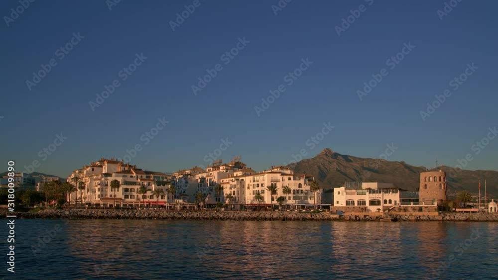 Gimbal time lapse shot of Puerto Banus Marbella, hotel with mountain view at daylight. Puerto Banus buildings sea coast in winter time under bright blue sky Gimbal time lapse shot of Puerto Banus Marbella, hotel with mountain view at daylight. Puerto Banus buildings sea coast in winter time under bright blue sky