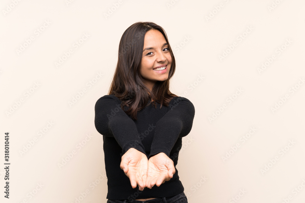 Young brunette woman with white sweater over isolated background holding copyspace imaginary on the palm to insert an ad Young brunette woman with white sweater over isolated background holding copyspace imaginary on the palm to insert an ad