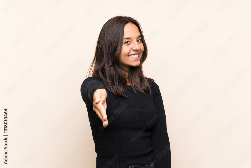 Young brunette woman with white sweater over isolated background shaking hands for closing a good deal Young brunette woman with white sweater over isolated background shaking hands for closing a good deal