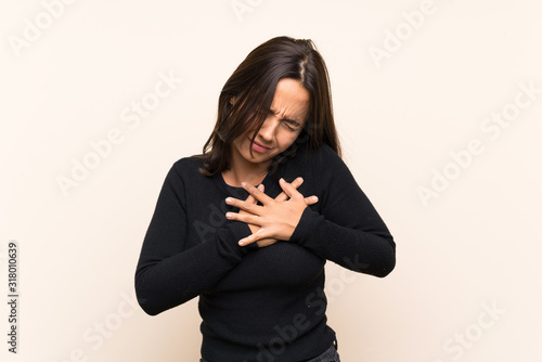 Young brunette woman with white sweater over isolated background having a pain in the heart © luismolinero