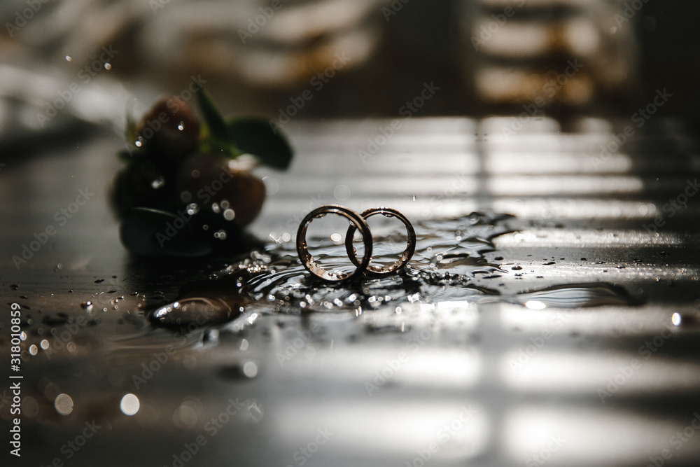 Beautiful toned picture with wedding rings lie on a wooden surface against the background of a bouquet of flowers Beautiful toned picture with wedding rings lie on a wooden surface against the background of a bouquet of flowers