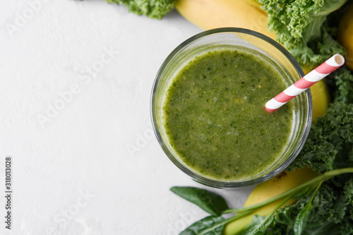 Freshly prepared glass of green smoothie, close-up. Fresh vegetable smoothie on a light background. Vegetable smoothie with spinach and kale cabbage.