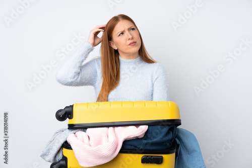 Traveler woman with a suitcase full of clothes having doubts and with confuse face expression photo