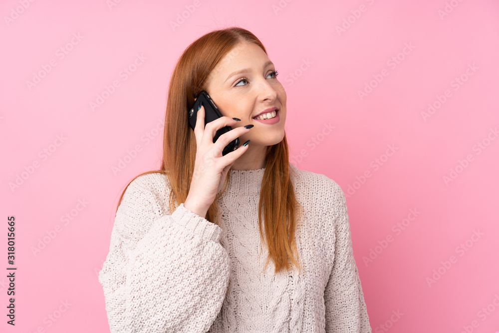 Young redhead woman over isolated pink background keeping a conversation with the mobile phone Young redhead woman over isolated pink background keeping a conversation with the mobile phone