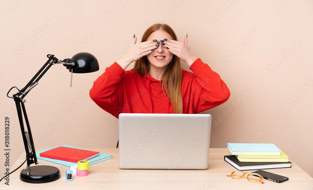 Young student woman in a workplace with a laptop covering eyes by hands Young student woman in a workplace with a laptop covering eyes by hands
