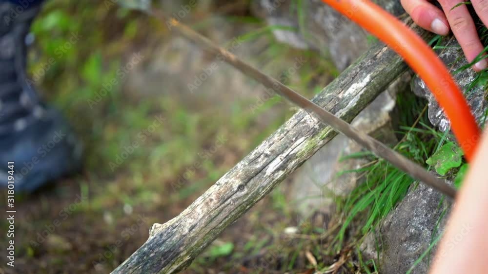 Boy sawing a stick with a handsaw, mountain, camping, slow motion Boy sawing a stick with a handsaw, mountain, camping, slow motion