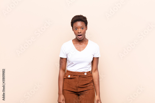 young pretty black womanlooking very shocked or surprised, staring with open mouth saying wow photo