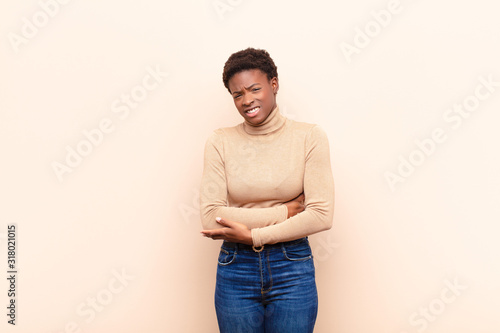 young pretty black womanfeeling anxious, ill, sick and unhappy, suffering a painful stomach ache or flu photo