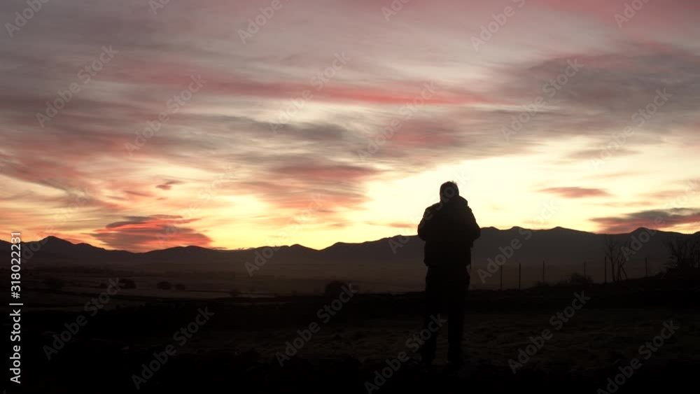 Photographer taking photographs of the sunrise while the sun rises through the mountains.Concept: Nature photographer Photographer taking photographs of the sunrise while the sun rises through the mountains.Concept: Nature photographer