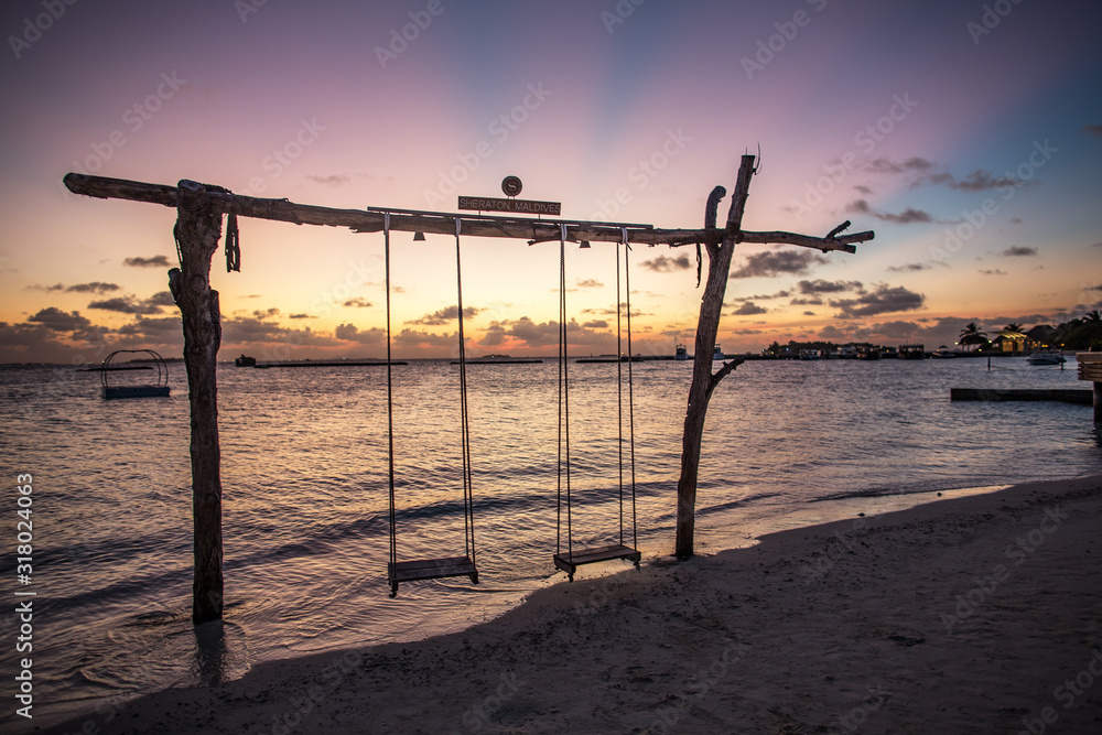 wooden swing on the beach at sunset
