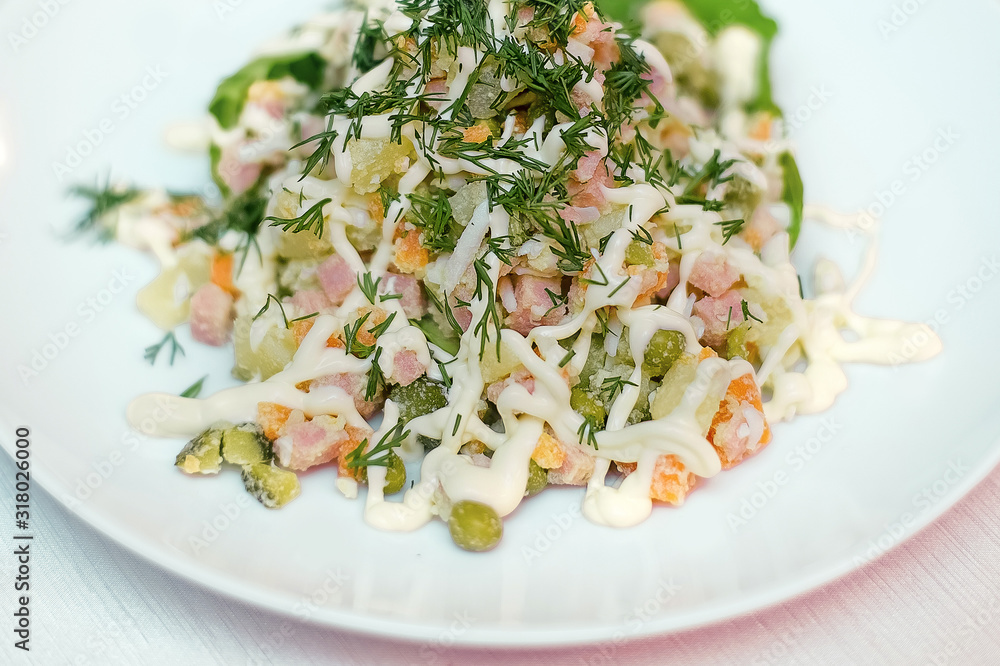 Russian salad with ham and green peas. Salad on a white plate. Russian salad with ham and green peas. Salad on a white plate.