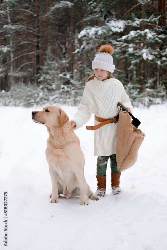 a little girl in white knitted clothes walks in the forest with her dog Labrador. looking for game or tree for home