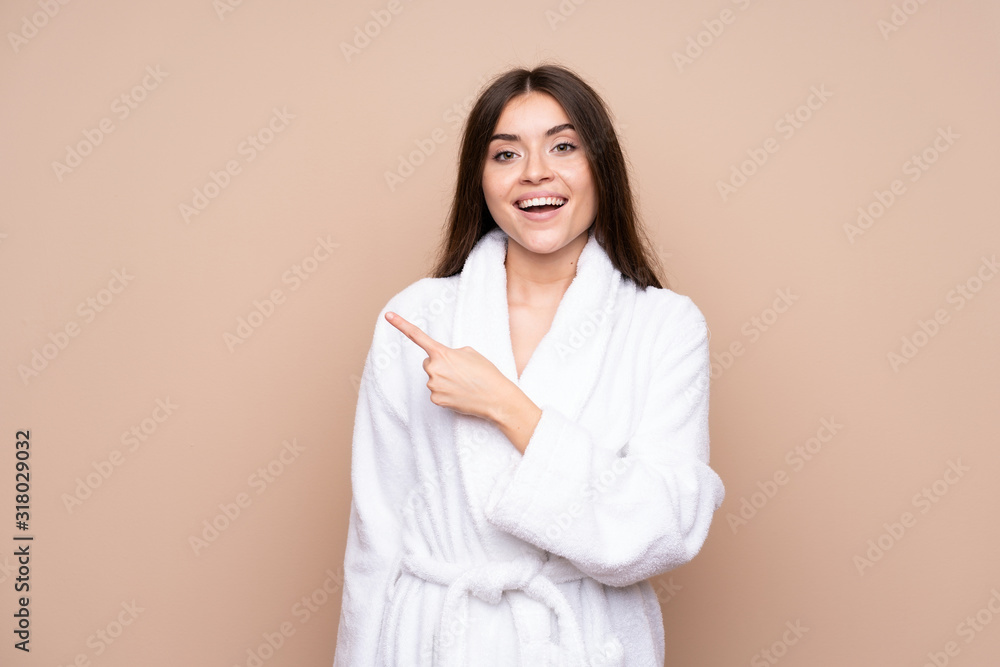 Young girl in a bathrobe over isolated background pointing finger to the side Young girl in a bathrobe over isolated background pointing finger to the side