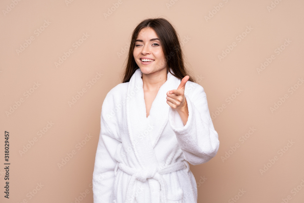 Young girl in a bathrobe over isolated background points finger at you Young girl in a bathrobe over isolated background points finger at you