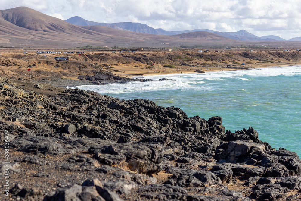 Panoramic view at the coastline of El Cotillo on canary island Fuerteventura with  lava rocks and mountain range in the  background
