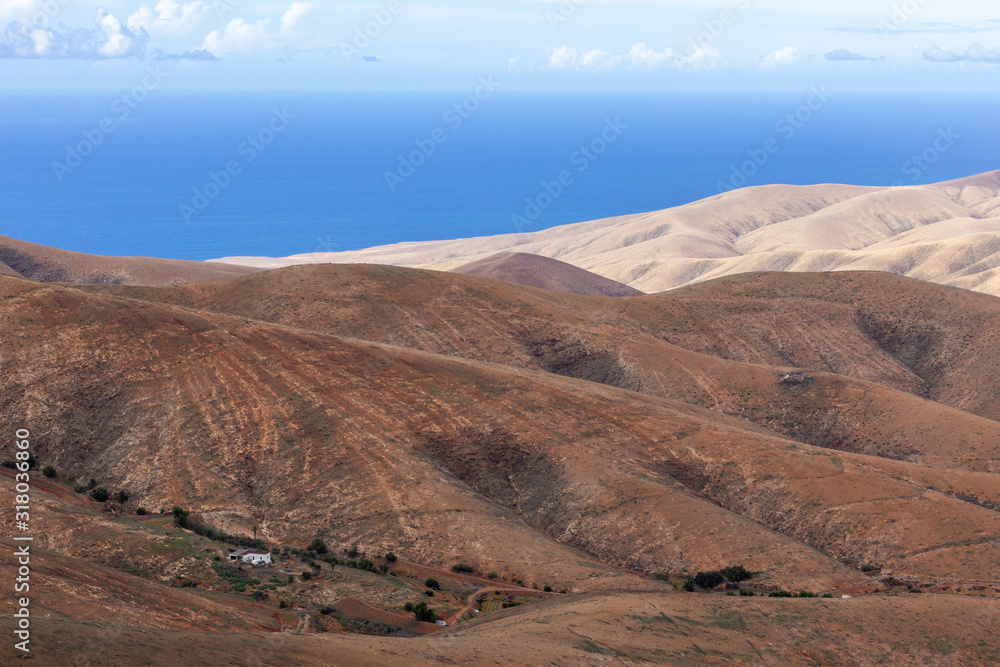 Panoramic view at landscape from viewpoint Mirador Morro Velosa on Fuerteventura with  multi colored volcanic mountainss and the Atlantic ocean in the background
