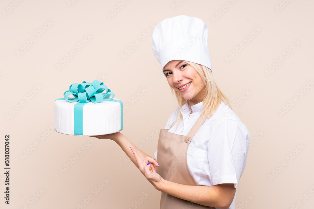 Young Russian woman with a big cake over isolated background and pointing it Young Russian woman with a big cake over isolated background and pointing it