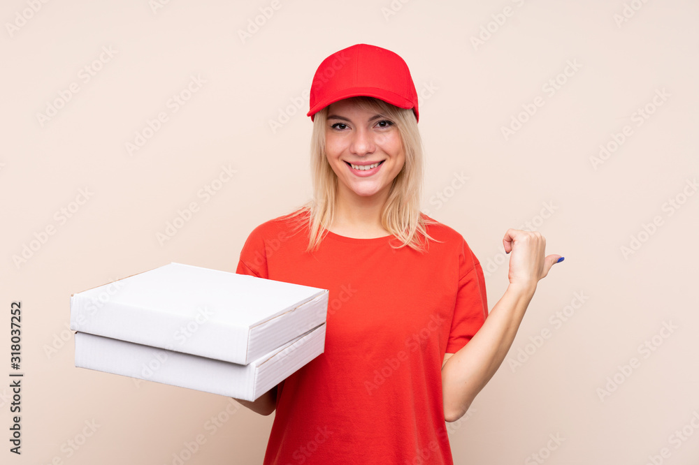 Pizza delivery Russian woman holding a pizza over isolated wall pointing to the side to present a product Pizza delivery Russian woman holding a pizza over isolated wall pointing to the side to present a product