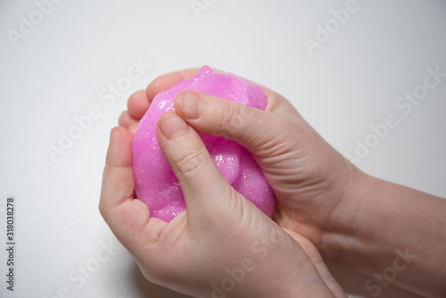 Child s hands close-up. The child kneads the mucus. The mucus is pink and shiny. Slime takes interesting forms.